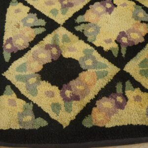 Close-up of a hooked rug with a yellow field, black diamond outlines, and floral motifs in purple, green, and orange hues, by Rugs On Net