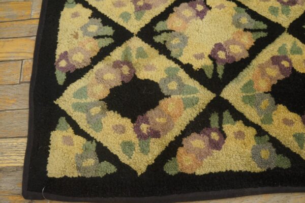 Close-up of a hooked rug with a yellow field, black diamond outlines, and floral motifs in purple, green, and orange hues, by rugs on net