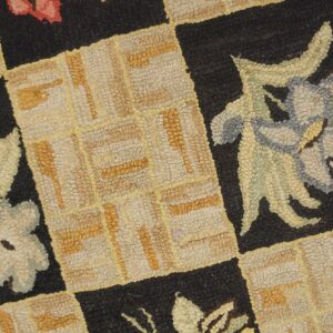 Close-up of a hooked rug featuring a checkerboard pattern with floral motifs in muted colors against black squares, by Rugs On Net