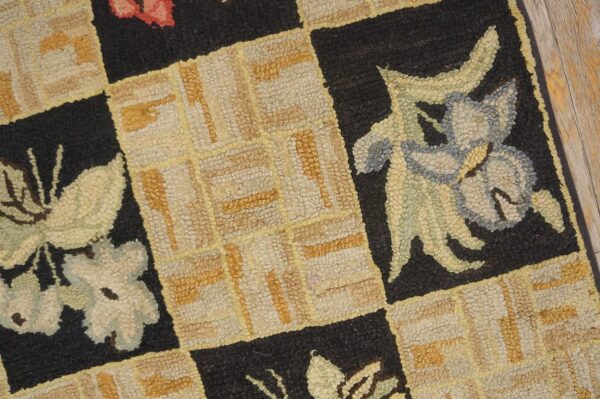 Close-up of a hooked rug featuring a checkerboard pattern with floral motifs in muted colors against black squares, by rugs on net