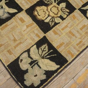 Close-up of a hooked rug with a checkerboard pattern featuring floral motifs in black squares and a tan geometric weave in between, by Rugs On Net. by Rugs On Net