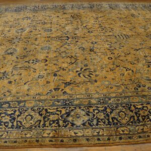 Close-up of a large antique rug with gold and navy floral patterns by Rugs On Net