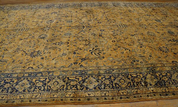 Close-up of a large antique rug with gold and navy floral patterns by rugs on net