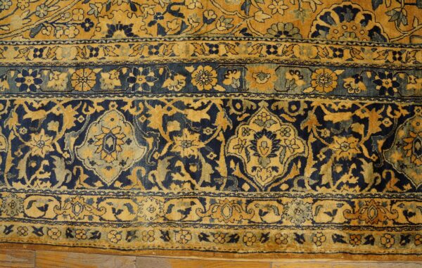 Close-up of a traditional persian rug border featuring intricate gold and navy blue floral motifs by rugs on net. By rugs on net