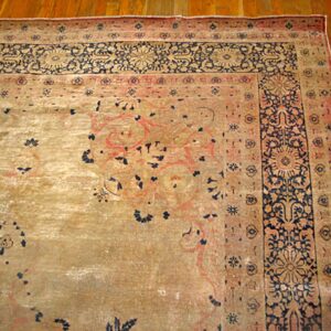 Close-up detail of a faded antique rug with beige field and dark blue border motifs by Rugs On Net. by Rugs On Net