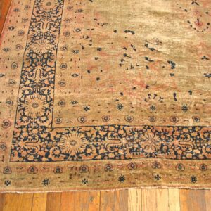 Close-up of a worn, antique rug border with navy blue floral details on a faded gold and tan field, by Rugs On Net