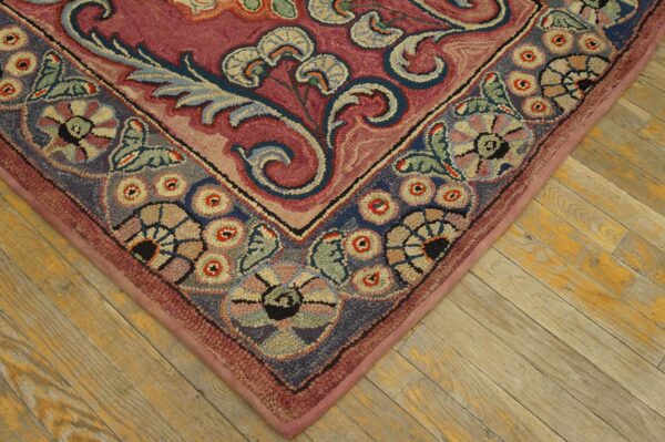 Close-up corner detail of a richly colored, floral hooked rug on wooden flooring by rugs on net. By rugs on net