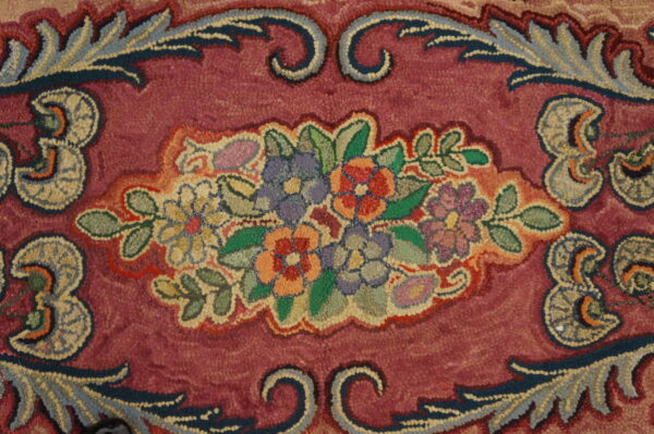 Close-up of a colorful floral medallion on a deep pink background of the hooked rug by rugs on net. By rugs on net