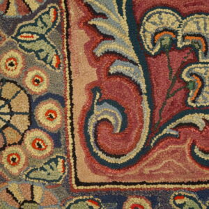 Close-up of a colorful hooked rug pattern featuring floral and scroll elements in pink, blue, and cream by Rugs On Net
