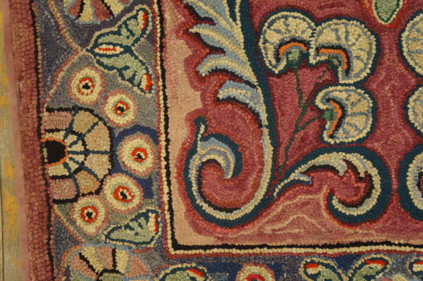 Close-up of a colorful hooked rug pattern featuring floral and scroll elements in pink, blue, and cream by rugs on net
