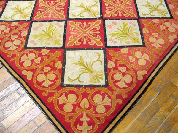 Close-up corner view of a red and cream needlepoint rug with a repeating square motif, by rugs on net