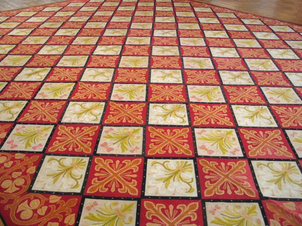 Close-up view of a large red and cream checkered rug with floral motifs, by rugs on net