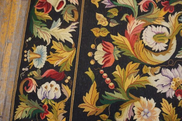 Close-up of a dark tapestry rug featuring vibrant floral and leaf motifs in shades of red, yellow, green, and white, by rugs on net. By rugs on net