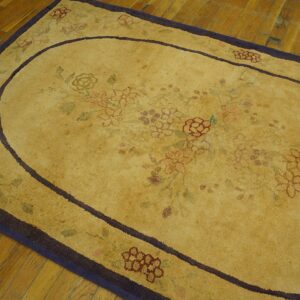 Close-up of a faded yellow rug with subtle floral patterns and a dark border, resting on hardwood floors, by Rugs On Net