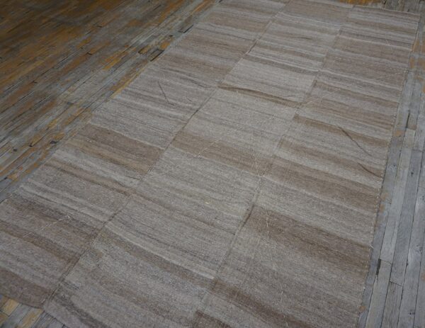 Close-up view of a neutral, striped kilim rug on a rustic wooden floor by rugs on net. By rugs on net