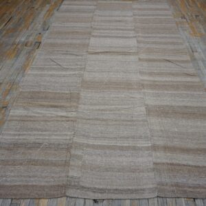 A flatweave rug with horizontal brown and beige stripes, laid on a distressed wooden floor, by Rugs On Net