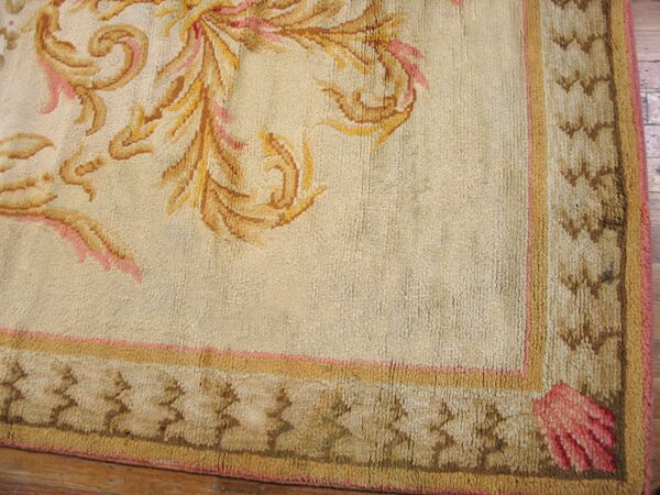 Close-up of a beige rug corner with gold and pink floral elements and a patterned border by rugs on net