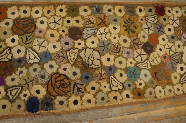 A close-up view of a colorful, folk-art style hooked rug featuring scattered floral and abstract shapes on a muted background, similar to the 'scattered blooms' rug by rugs on net. By rugs on net