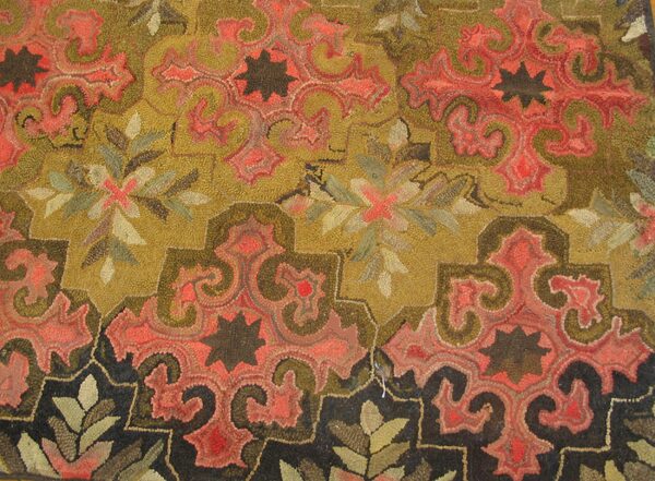 Close-up of a hooked rug featuring swirling red and olive green patterns on a gold background, by rugs on net