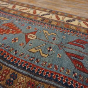 Close-up of a vintage blue rug with red and tan geometric motifs by Rugs On Net