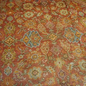 Close-up of a richly colored, distressed rug with terracotta, gold, and muted blue-green floral motifs, by Rugs On Net. by Rugs On Net