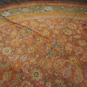 Close-up of a round, distressed terracotta and gold floral rug by Rugs On Net. by Rugs On Net
