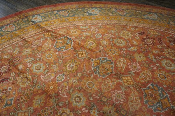 Close-up of a round, distressed terracotta and gold floral rug by rugs on net. By rugs on net