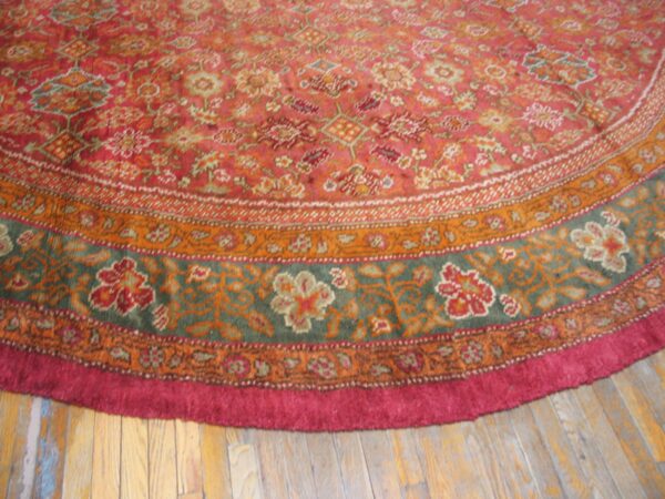 Close-up of a round rug with intricate floral patterns in red, orange, and green tones, by rugs on net. By rugs on net