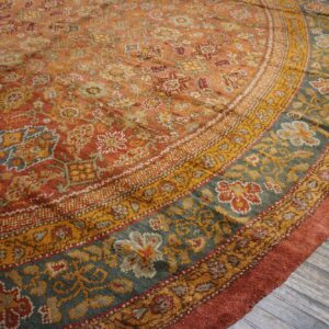 Close-up of a round, richly colored rug featuring intricate floral and geometric patterns in rust, gold, and teal by Rugs On Net. by Rugs On Net