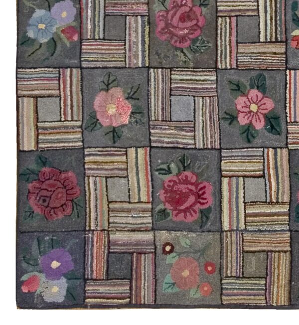 Close-up of a hooked rug featuring a patchwork design with floral motifs in muted pinks, blues, and purples against a dark gray background, by rugs on net. By rugs on net