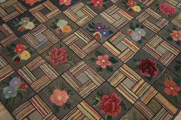 Close-up of a hooked rug featuring a repeating block pattern with colorful floral motifs on a dark ground, by rugs on net