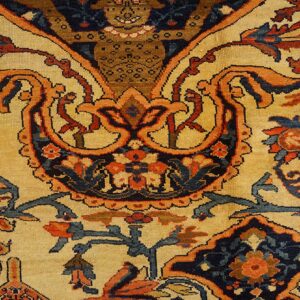 Close-up of a traditional rug pattern featuring intricate floral and curvilinear motifs in orange, blue, and dark accents on a beige field, by Rugs On Net