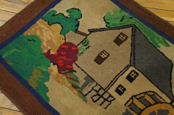 Close-up of a hooked rug featuring a stylized house and landscape in earthy tones, by rugs on net. By rugs on net