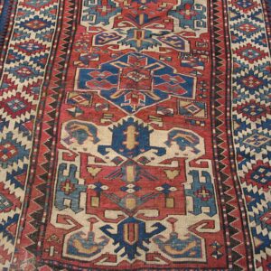 Close-up of a vintage Caucasian rug with bold red and blue geometric patterns by Rugs On Net. by Rugs On Net