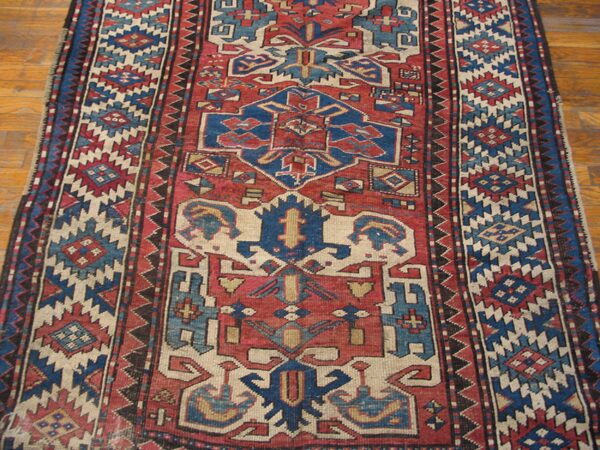 Close-up of a vintage caucasian rug with bold red and blue geometric patterns by rugs on net. By rugs on net