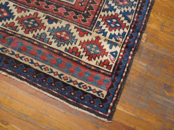 Close-up corner of a tribal rug with red, blue, and cream geometric patterns by rugs on net. By rugs on net