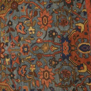 Close-up of an antique rug featuring blue, red, and gold floral motifs on a muted blue ground, by Rugs On Net. by Rugs On Net