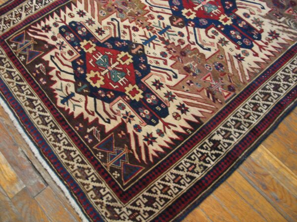 Close-up of a tribal rug with geometric patterns in red, blue, and cream on a wooden floor, by rugs on net