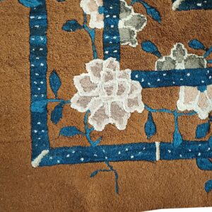Close-up of a brown rug corner featuring blue border accents and light floral motifs by Rugs On Net. by Rugs On Net