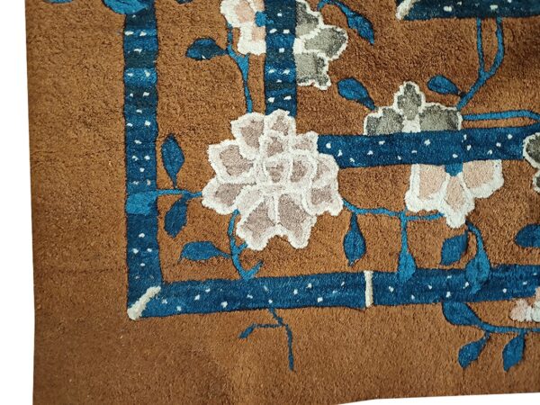 Close-up of a brown rug corner featuring blue border accents and light floral motifs by rugs on net. By rugs on net