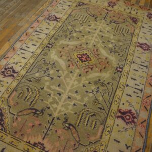 Close-up of an olive green and beige area rug with abstract floral motifs on a wooden floor by Rugs On Net. by Rugs On Net