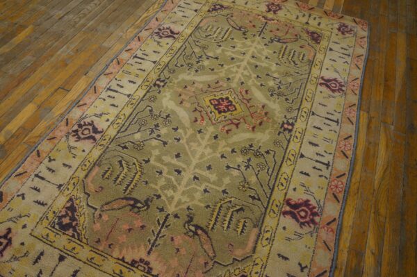 Close-up of an olive green and beige area rug with abstract floral motifs on a wooden floor by rugs on net. By rugs on net