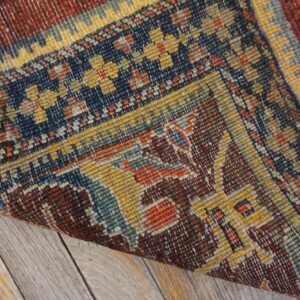 Close-up of the corner of a richly patterned, vintage rug with deep blues, reds, and yellows, showing texture and border detail by Rugs On Net. by Rugs On Net
