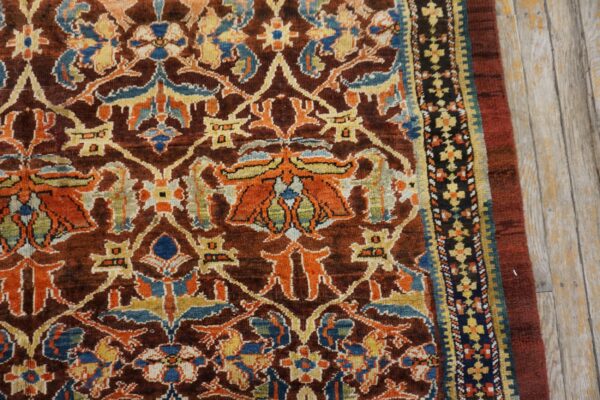 Close-up of a richly colored, dark brown rug featuring intricate floral and geometric patterns in orange, blue, and yellow, by rugs on net. By rugs on net