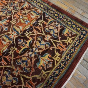 Close-up of a richly patterned, dark brown rug with orange and blue accents on a weathered wood floor by Rugs On Net