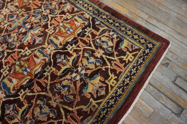 Close-up of a richly patterned, dark brown rug with orange and blue accents on a weathered wood floor by rugs on net