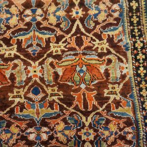 Close-up of a richly colored antique rug with brown, orange, and blue floral motifs by Rugs On Net