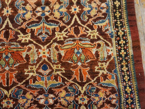 Close-up of a richly colored antique rug with brown, orange, and blue floral motifs by rugs on net