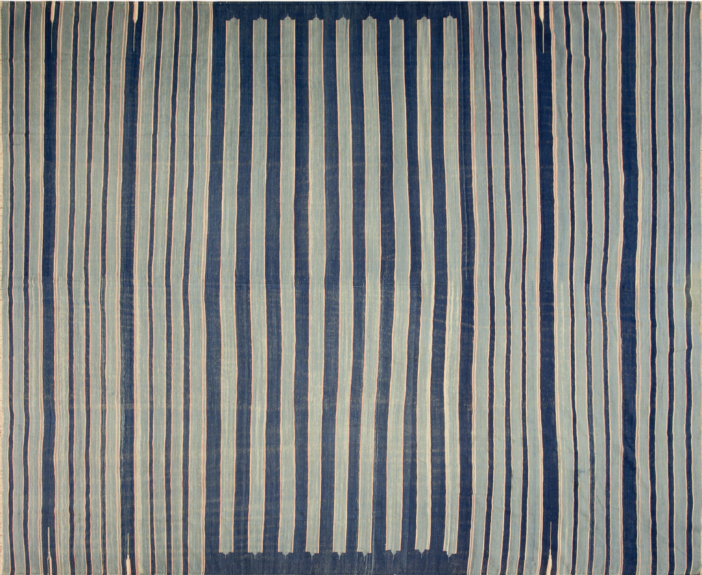 Vertical striped rug in shades of indigo and light blue with thin pink accents and a central rectangular panel by rugs on net