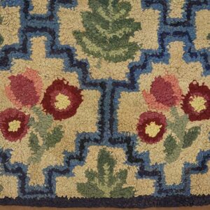Close-up of a hooked rug featuring stylized red and pink flowers with green leaves against a tan background, bordered by blue geometric shapes. This is the Floral Hooked Rug by Rugs On Net. by Rugs On Net